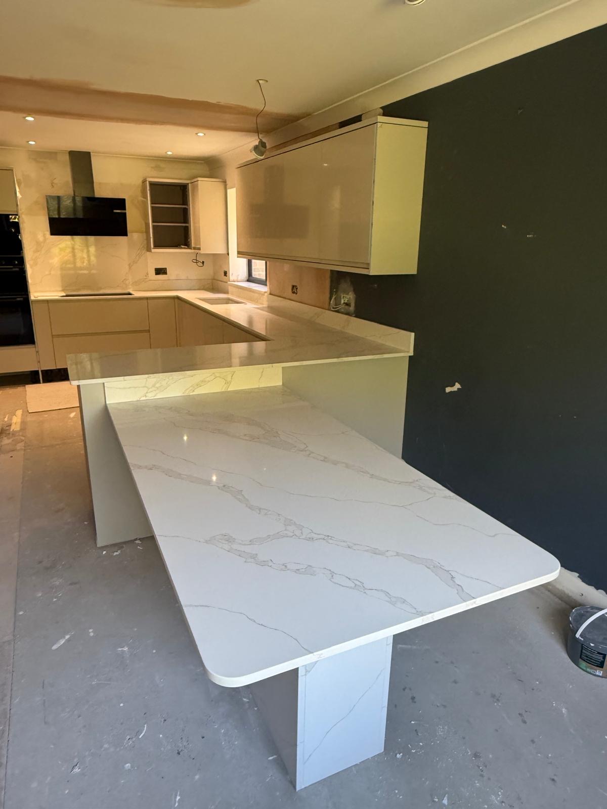 Calacatta quartz breakfast bar and worktops in cream handleless kitchen