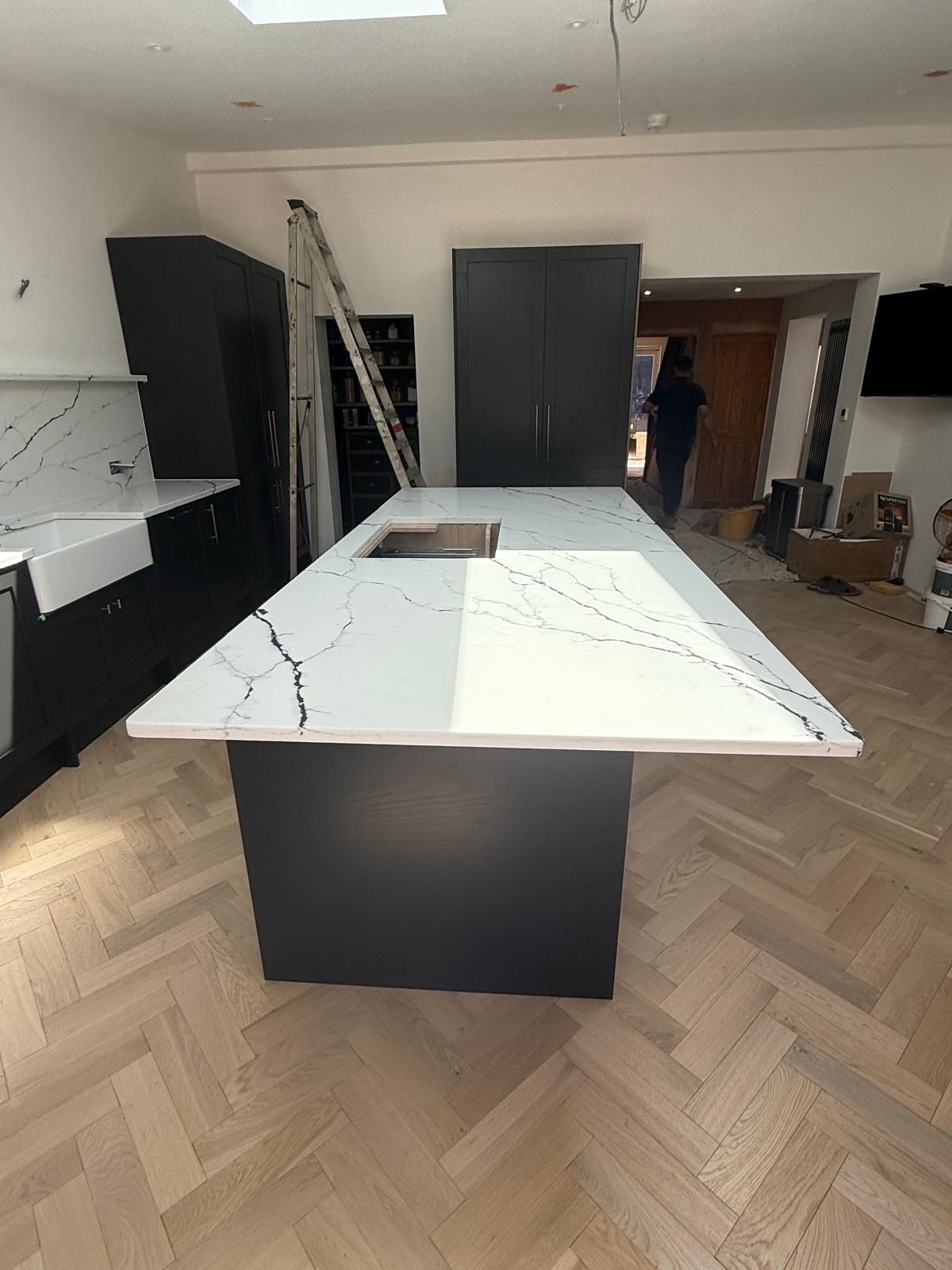Statuario quartz island with dramatic veining and dark shaker cabinets