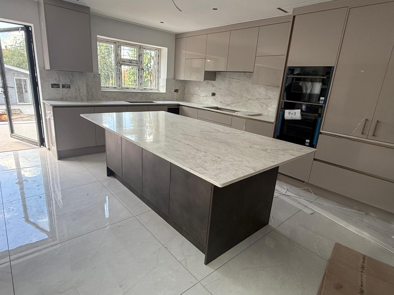 Handleless kitchen with white marble-effect island and stone backsplash