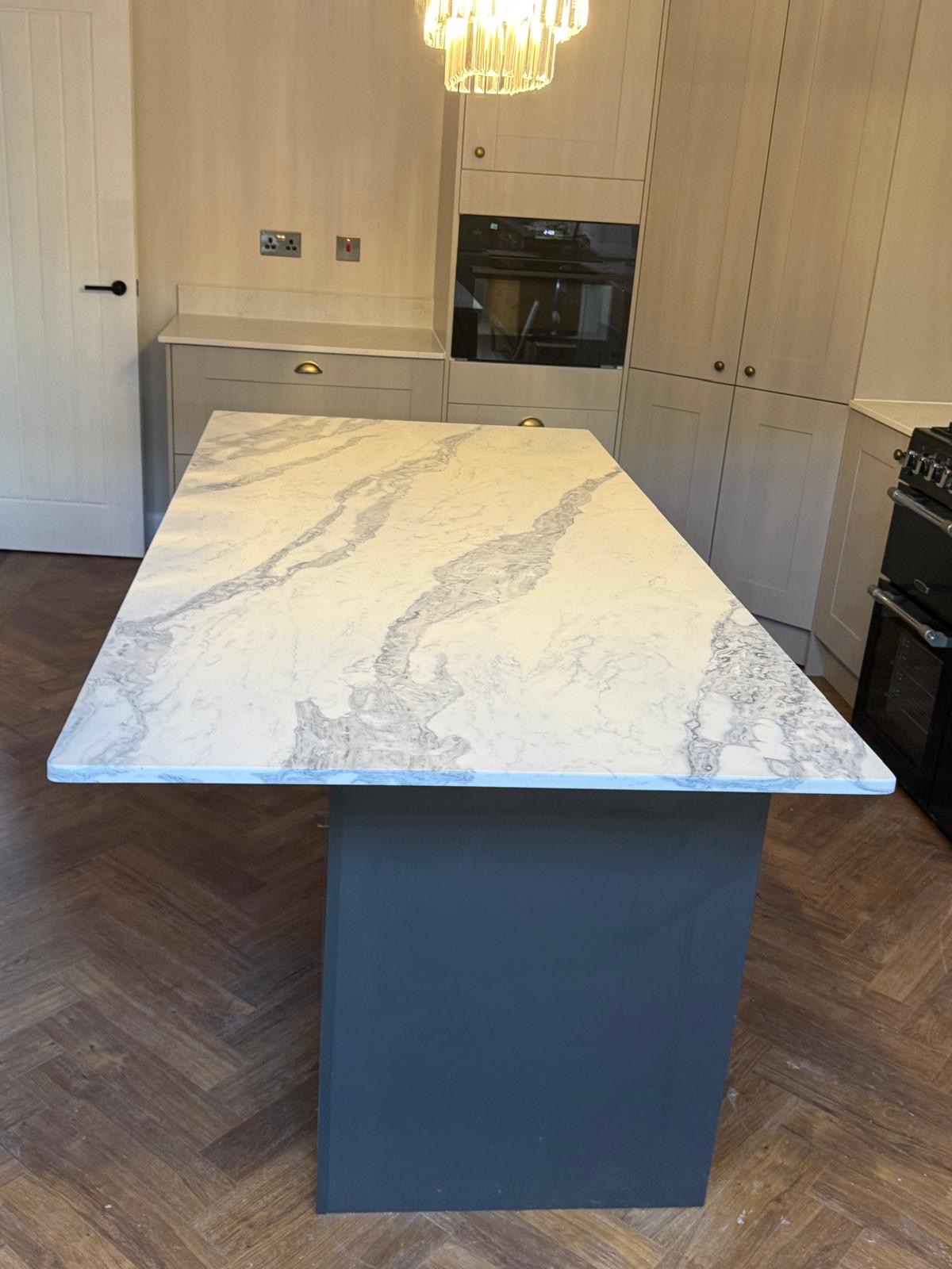 White marble island worktop on navy blue base in shaker kitchen